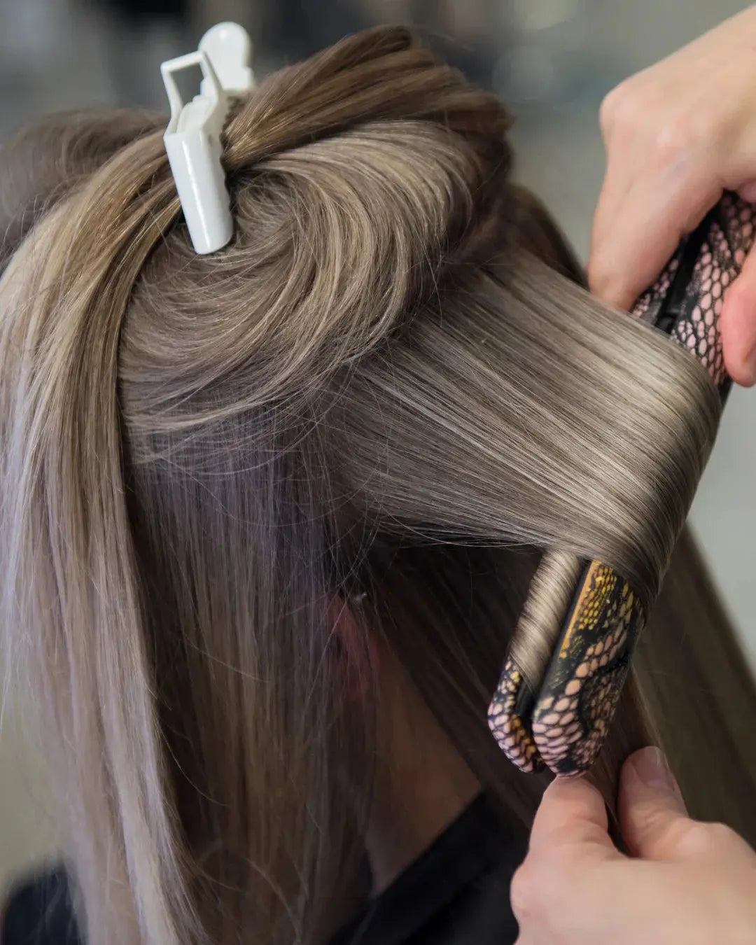 jeune femme se fait lisser les cheveux par une autre personne