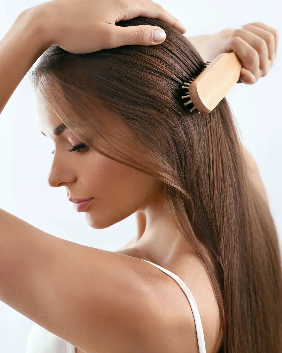 femme de profil qui se coiffe avec une brosse à cheveux