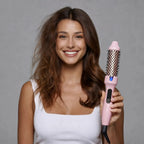 femme qui tient la brosse chauffante LumyHair dans ses mains. Elle souris et a un côté des cheveux fait avec la brosse te l'autre côté pas fait